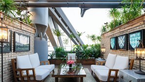 A patio area with two white cushioned sofas, a glass-top coffee table, and a metal trunk. - Hotel Eclat Beijing (Beijing)