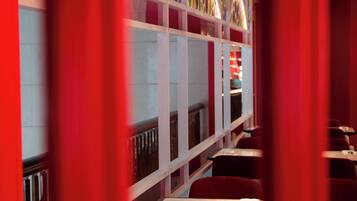 A restaurant with a red and white color scheme, featuring a long counter with seating and a decorative glass wall in the background.