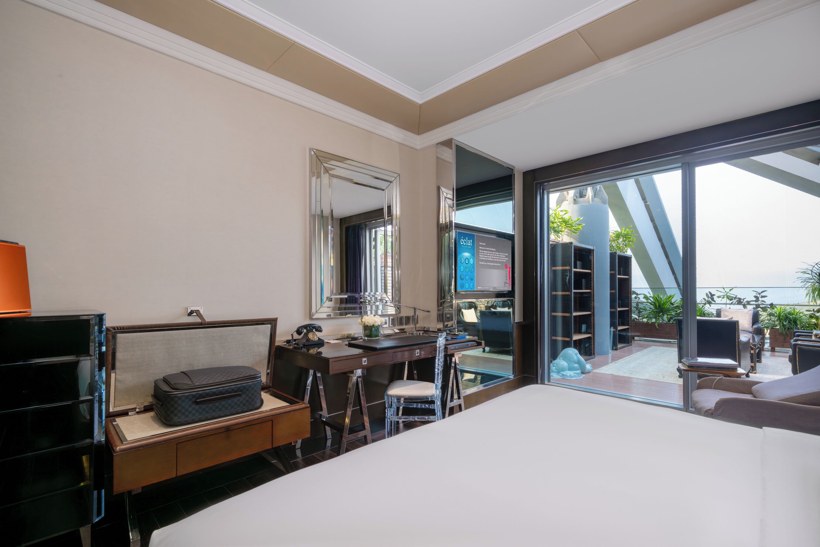 Una camera d'albergo con un letto, una scrivania, una sedia e un'ampia finestra con vista all'esterno.