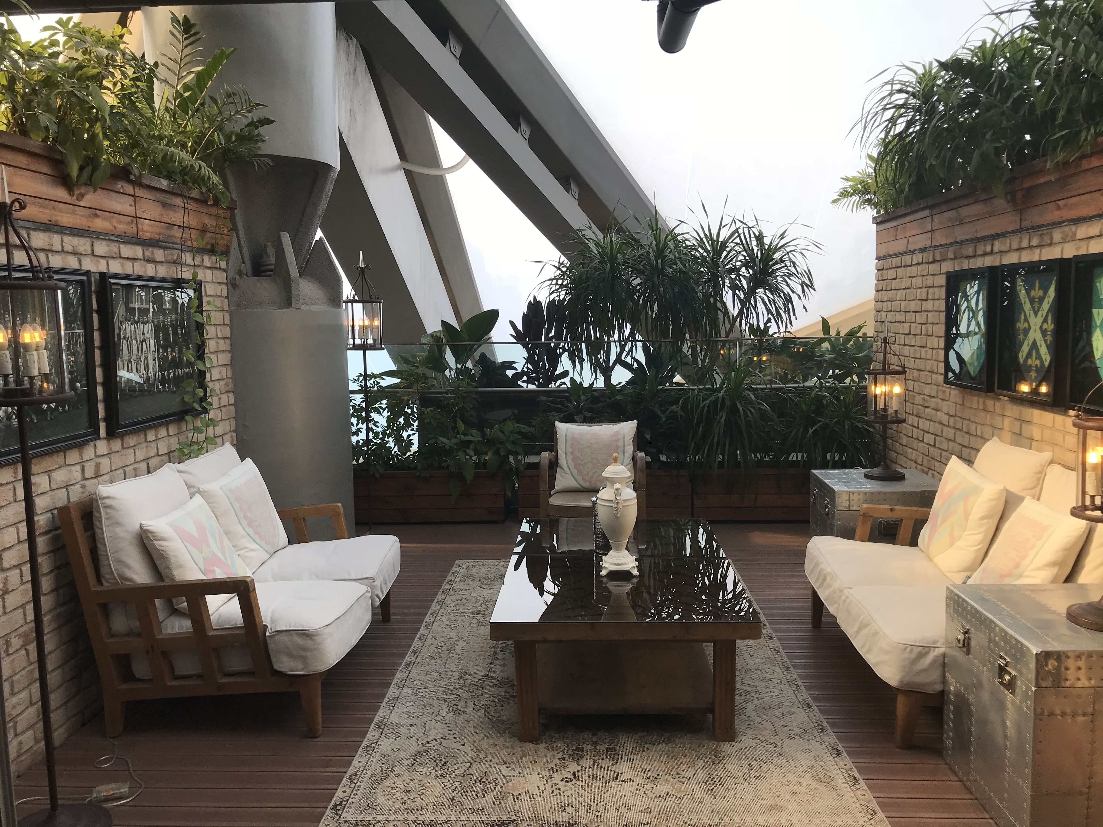 Una terrazza panoramica con mobili in legno, un tavolino in vetro e piante in vaso.