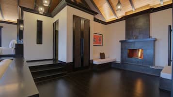 Un interior moderno con chimenea, suelo de madera oscura y una escalera que sube a otro nivel.