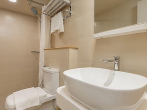 Un baño con lavamanos blanco, inodoro y zona de ducha.