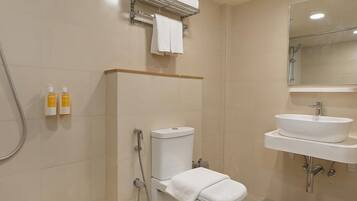 A bathroom with a toilet, a sink, and a shower. There are two bottles of toiletries on the wall.