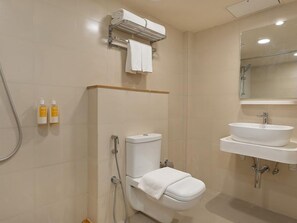 A bathroom with a toilet, a sink, and a shower. There are two bottles of toiletries on the wall.