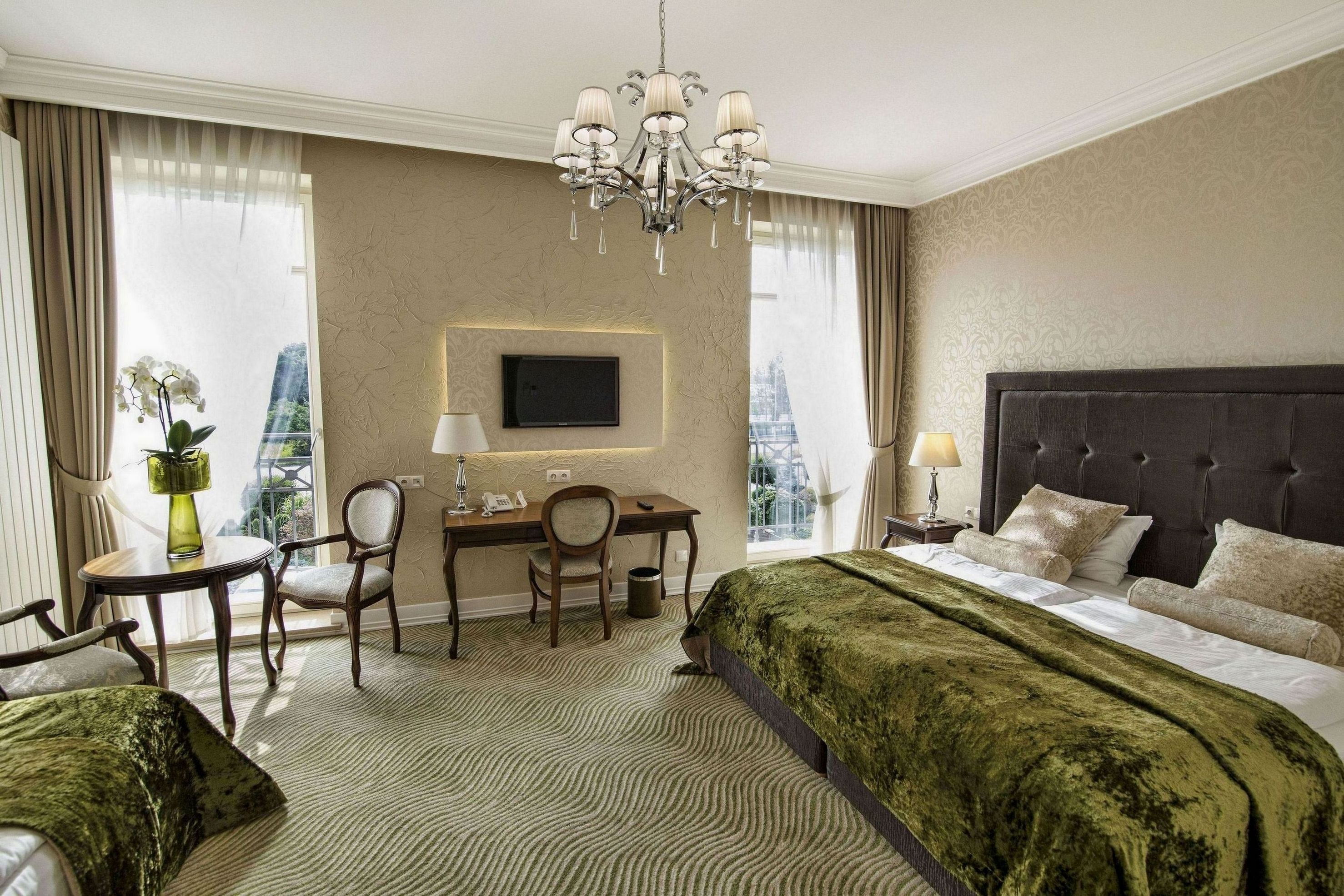 Habitación de hotel con una cama grande, un escritorio con silla, televisión y vistas a la ciudad.