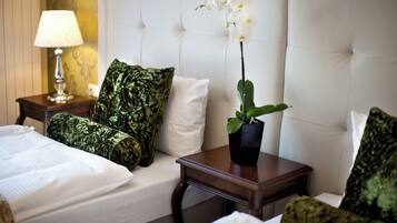 A hotel room with a bed, a nightstand with a lamp, a potted orchid, and a tufted headboard.