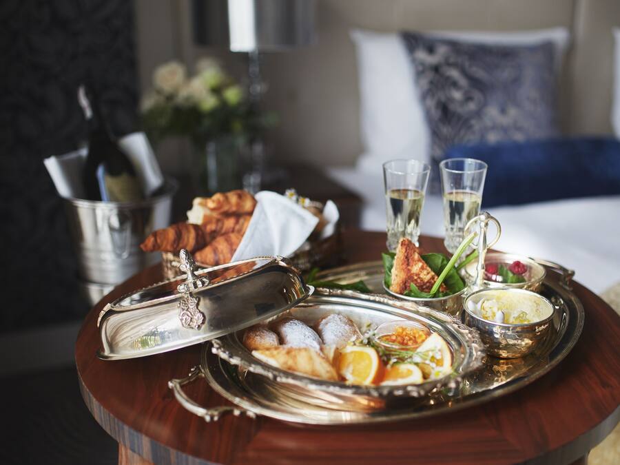 A breakfast tray with eggs, toast, and beverages on a wooden table in a hotel room.