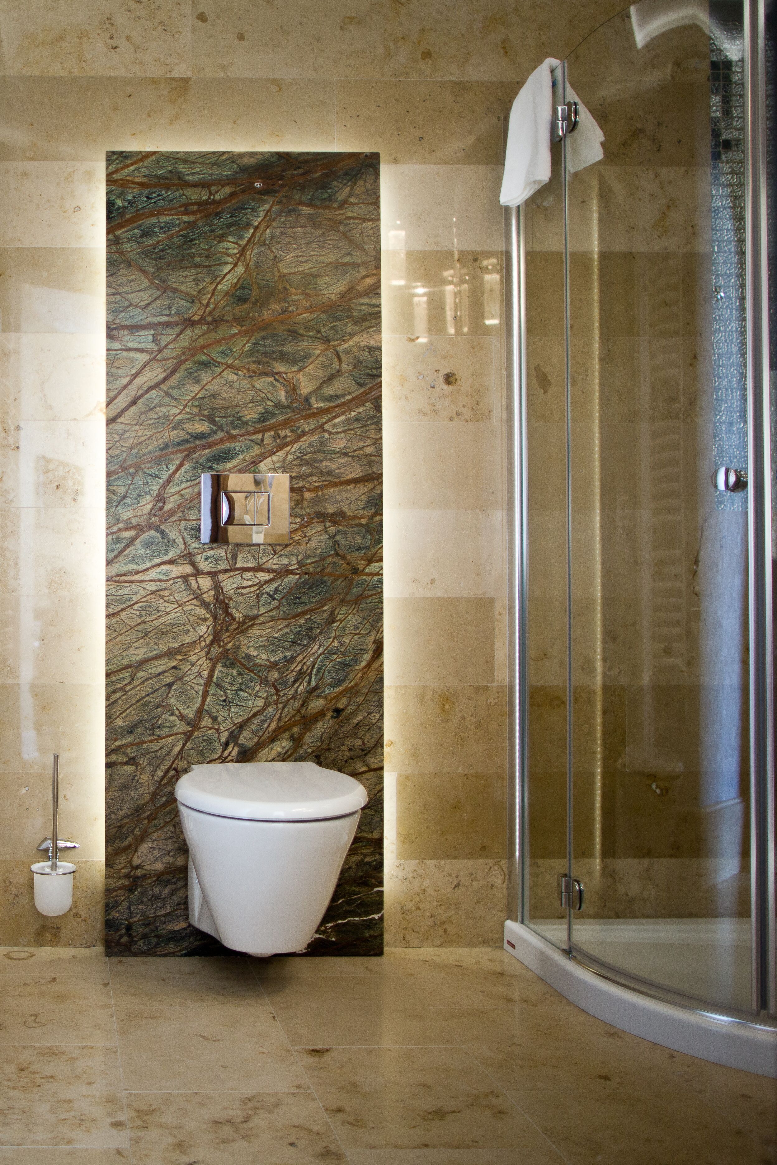 A modern bathroom with a marble wall, a toilet, and a glass shower enclosure.