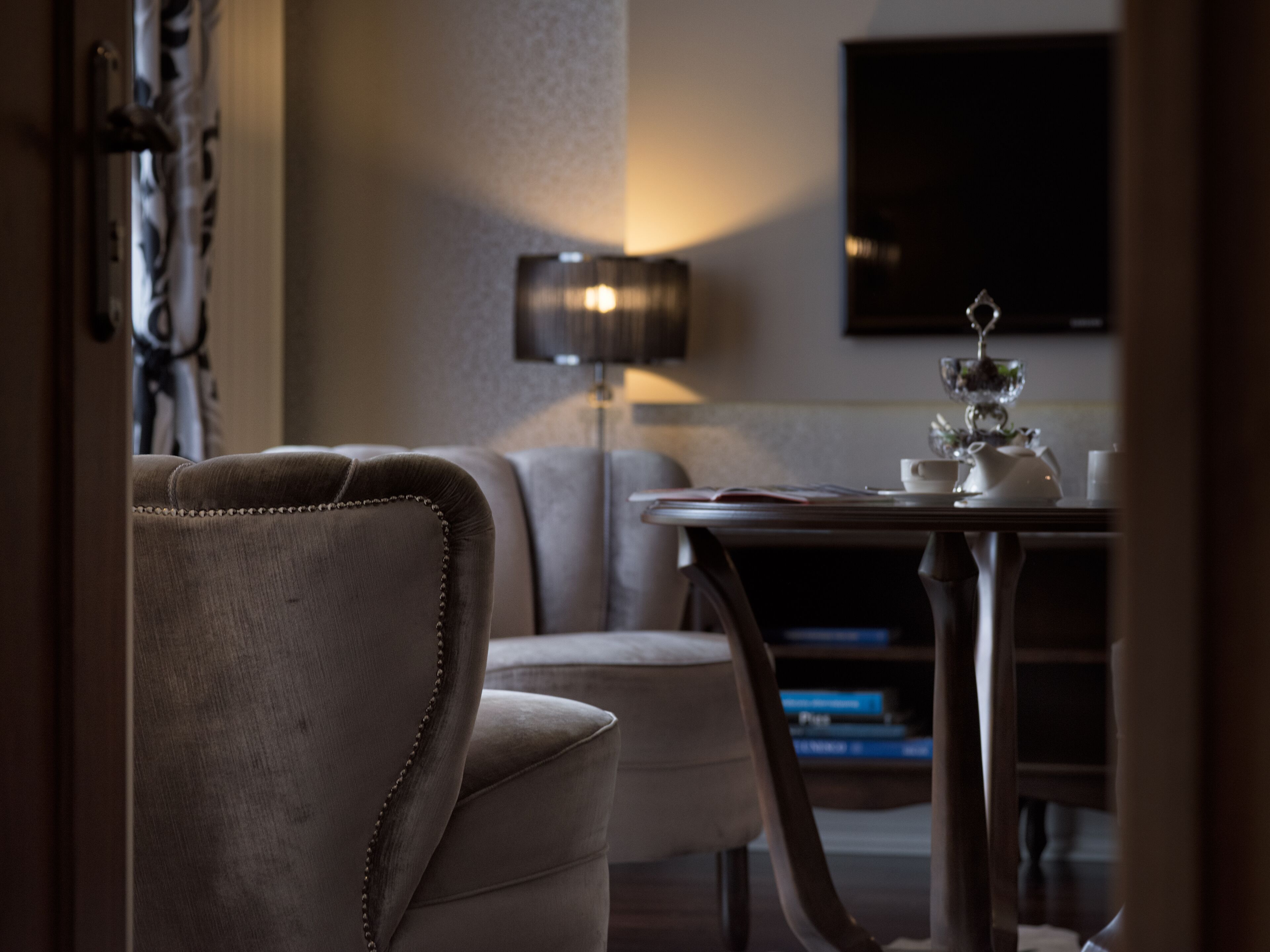 Un espacio de sala acogedor con un sofá, una mesa con tetera y una lámpara.