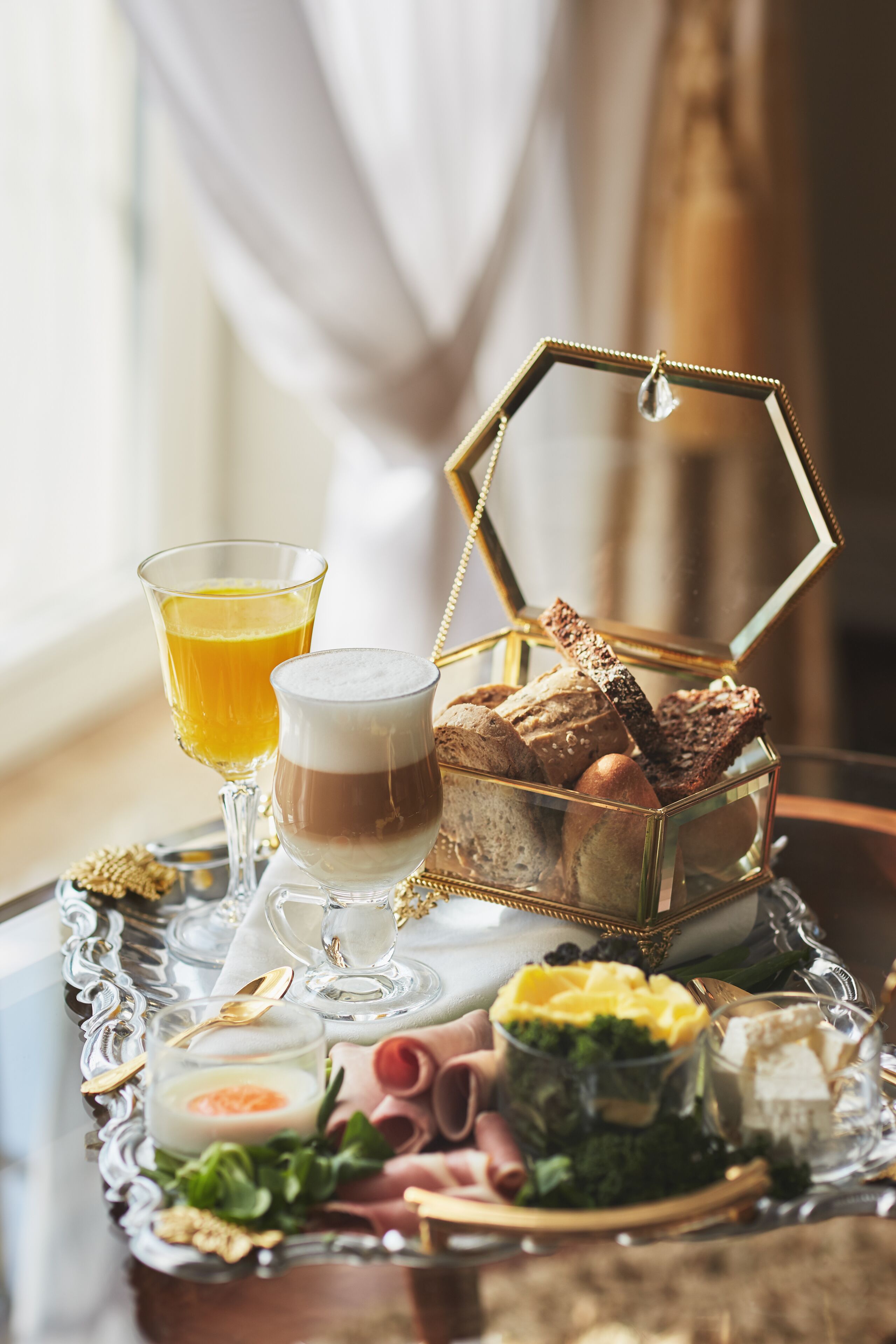 Un vassoio della colazione con diversi cibi e bevande, tra cui pane, formaggio e un bicchiere di succo d'arancia.