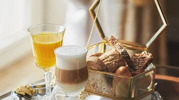 Un vassoio della colazione con diversi cibi e bevande, tra cui pane, formaggio e un bicchiere di succo d'arancia.