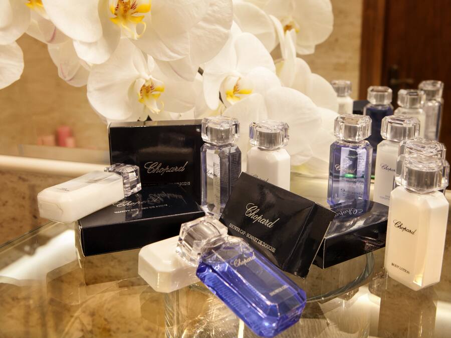 A display of Chopard perfume bottles and boxes on a glass table with white orchids in the background.