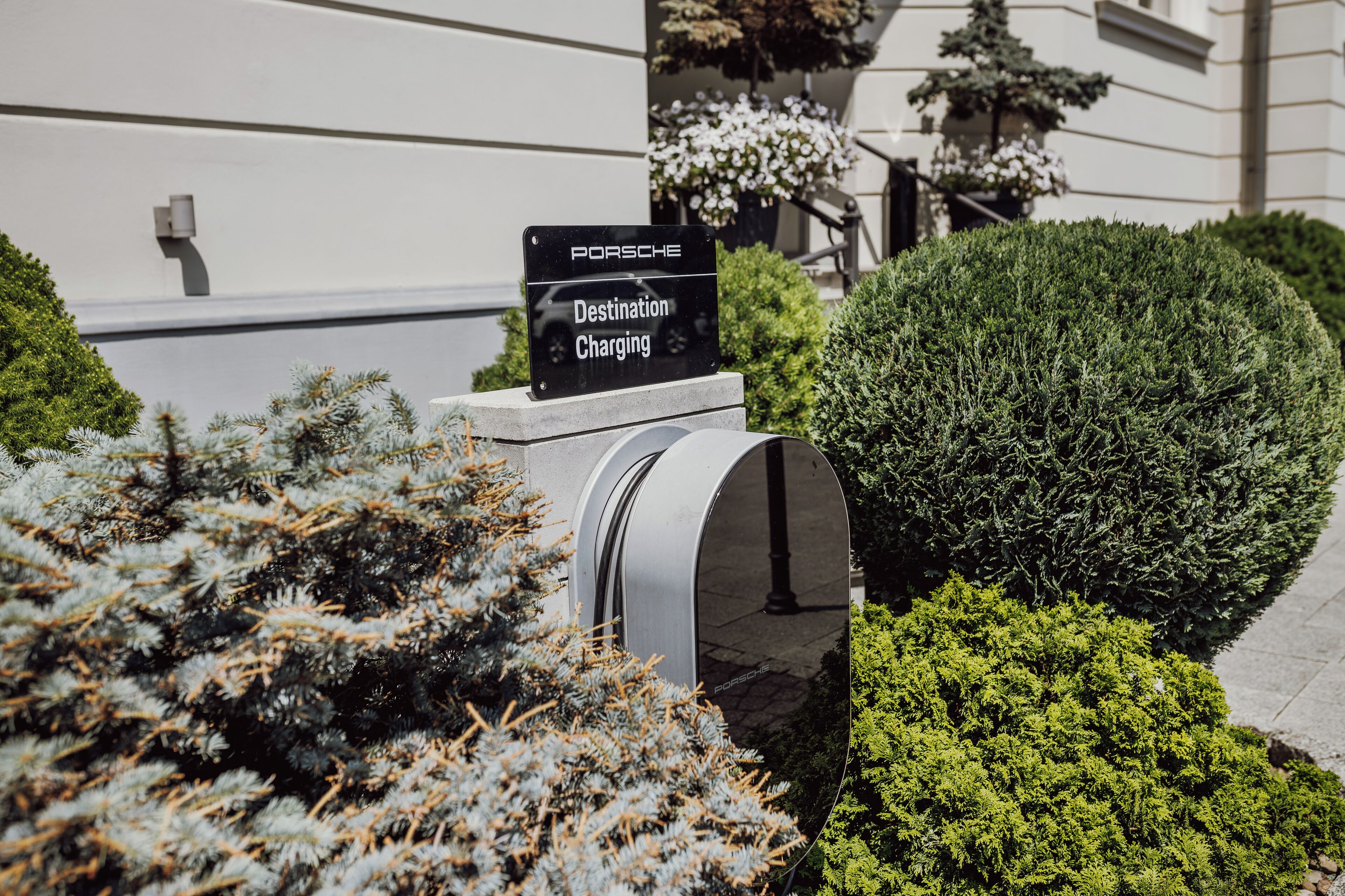 A sign for Porsche Destination Charging, a mailbox, and well-maintained bushes.