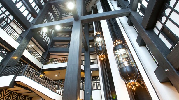 Ein mehrgeschossiges Atrium mit modernem architektonischen Design, ausgestattet mit einer zentralen Treppe und dekorativer Beleuchtung.