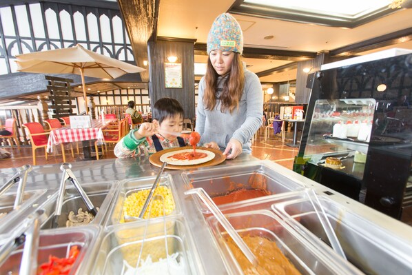 Un espace buffet avec différents récipients contenant de la nourriture et une personne qui sert à manger à un enfant.