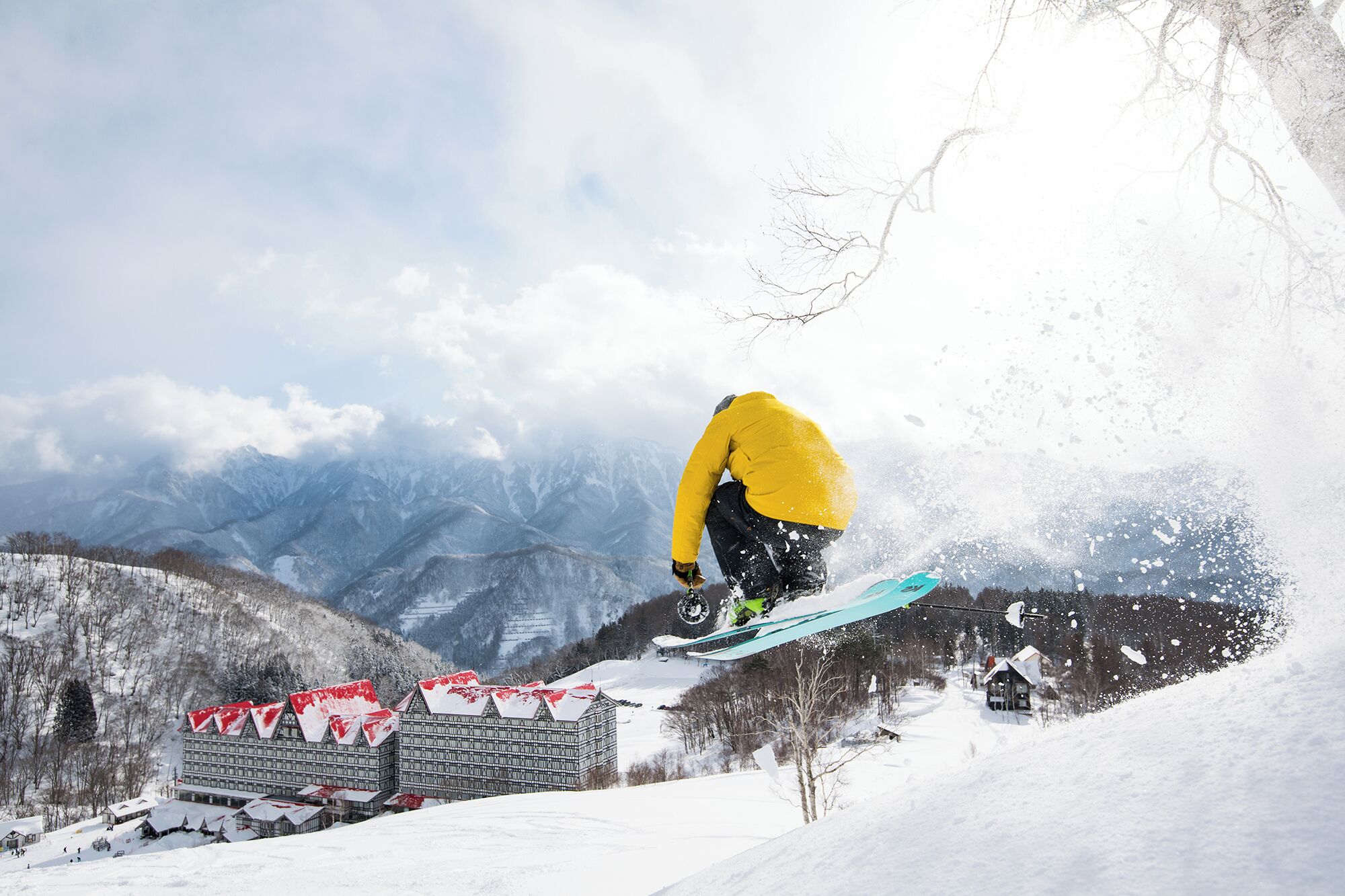 A snowboarder performing a jump with a mountainous backdrop.