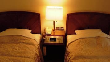 Habitación de hotel con dos camas, una lámpara de noche, un teléfono y un cartel con el número de la habitación.