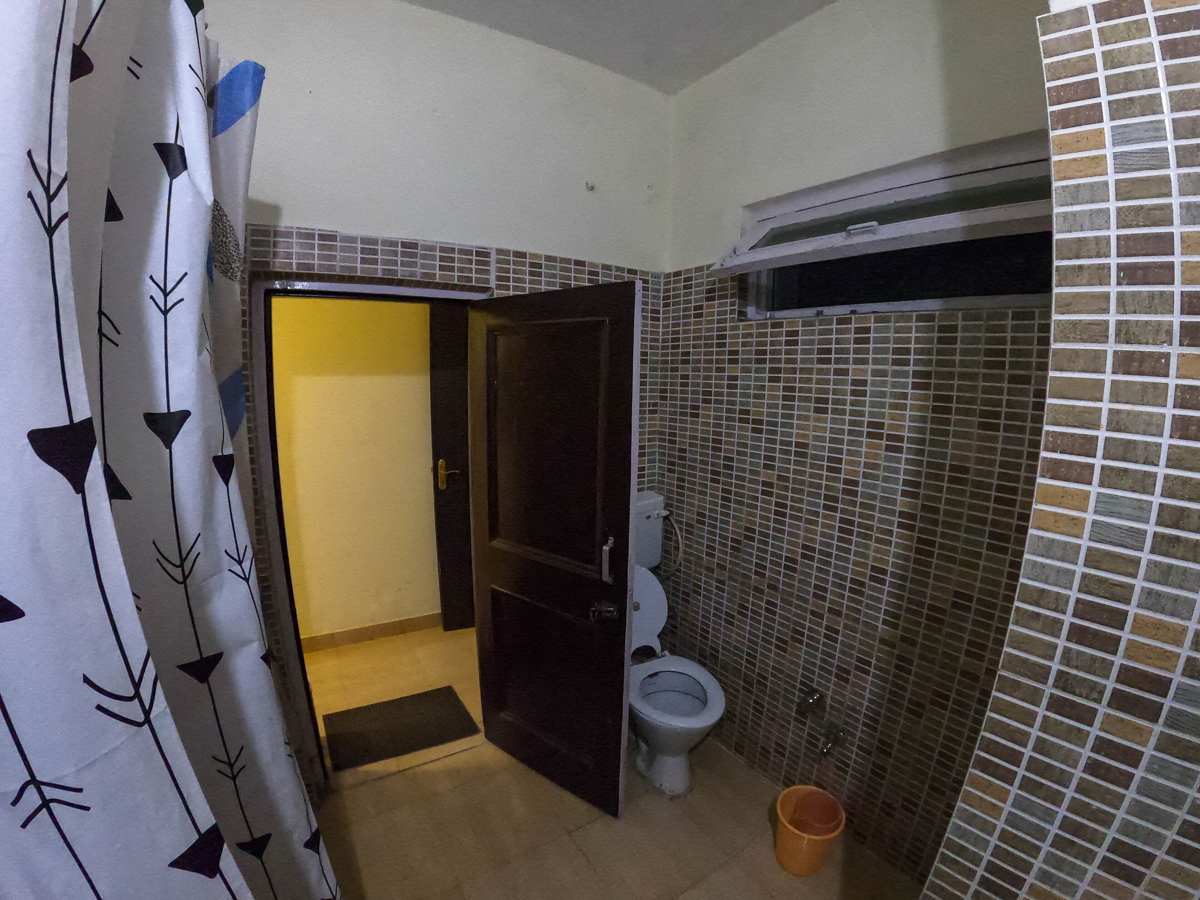 Un baño con inodoro, zona de ducha y pared con azulejos.