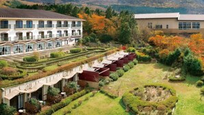 Un hotel con varias construcciones, un jardín bien cuidado y montañas al fondo.