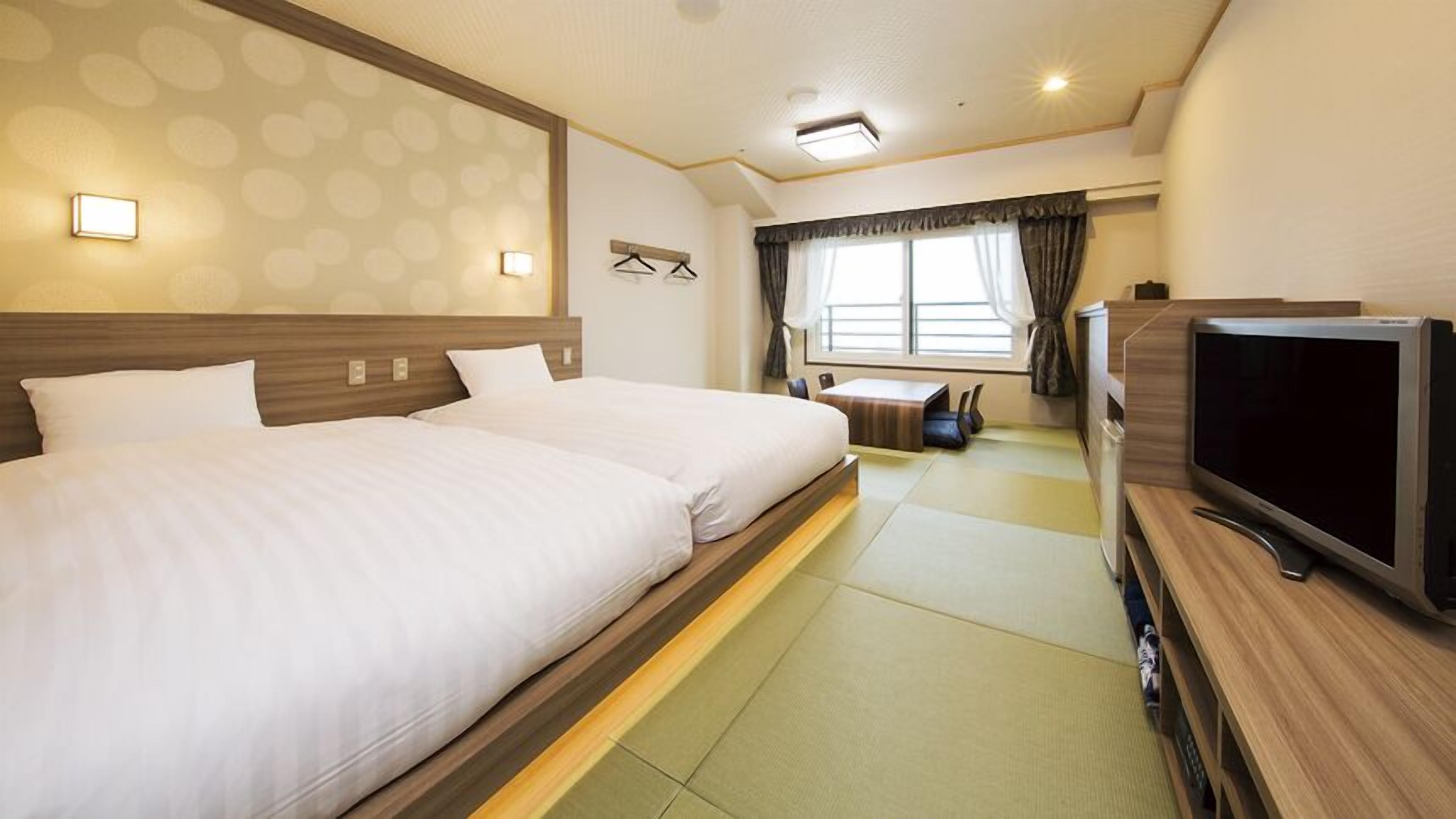 Quarto de hotel com uma cama grande, televisão e uma pequena área de estar.