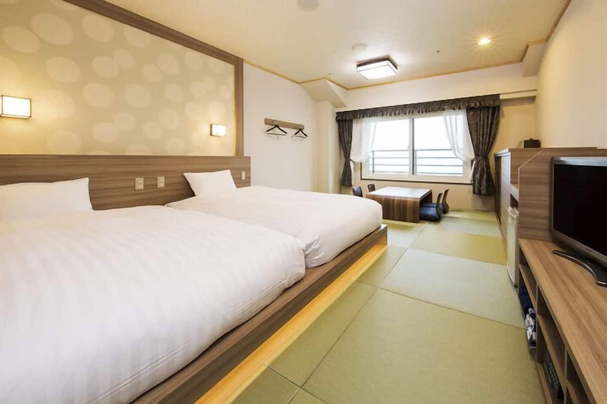 Ein Hotelzimmer mit einem großen Bett, einem Fernseher und einer kleinen Sitzecke.