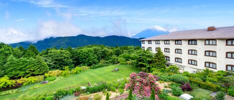 A hotel with a garden and a view of a mountain.