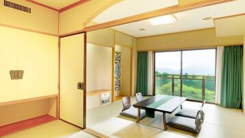 A traditional Japanese-style room with tatami flooring, a low table, and a view of greenery through large windows.