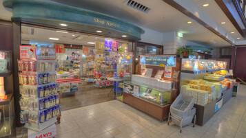 A store interior with shelves stocked with various products, a display counter with items, and a sign above the entrance reading "Shop Apricot".