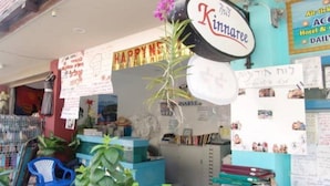 A room with a sign reading "Kinnatee," a blue chair, and various items on shelves.