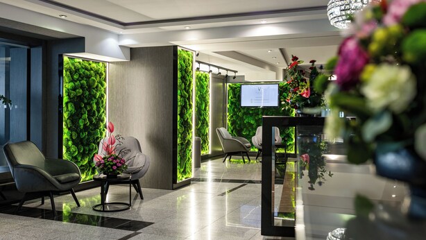 A lobby with a green wall, modern chairs, a reception desk, and a chandelier. - Vanilla Aparthotel (Kraków)