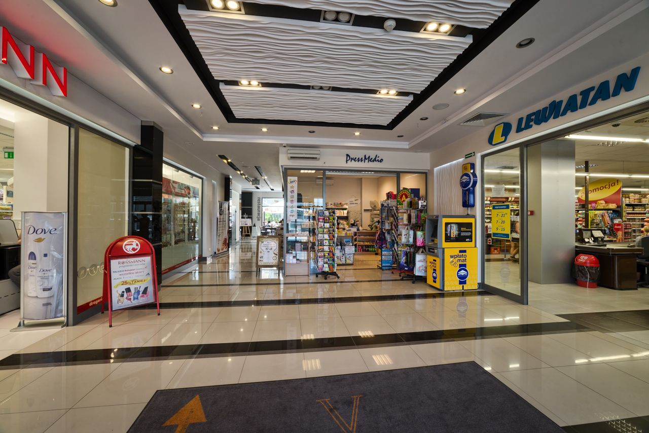 A shopping mall interior with stores like Dove, Dress Media, and Leuatan.