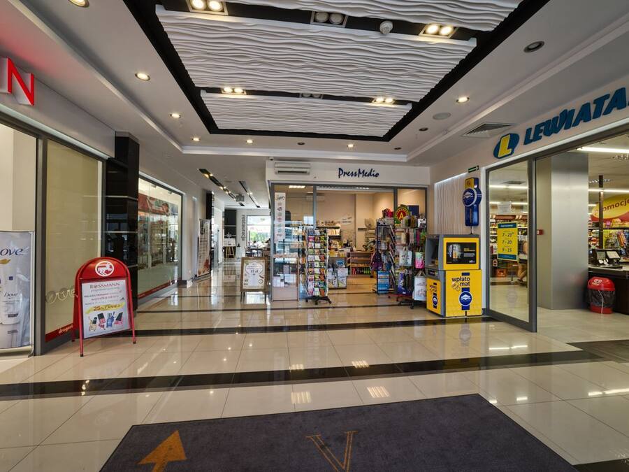 A shopping mall interior with stores like Dove, Dress Media, and Leuatan.