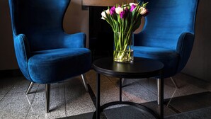 Two blue chairs, a small round table with a vase of flowers, and a framed sign on the wall. - Vanilla Aparthotel (Kraków)