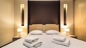 A hotel room with a large bed, two bedside lamps, and a headboard with vertical lighting. - Vanilla Aparthotel (Kraków)