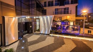 A modern hotel entrance with a glass facade, a reception area, and outdoor seating. - Vanilla Aparthotel (Kraków)