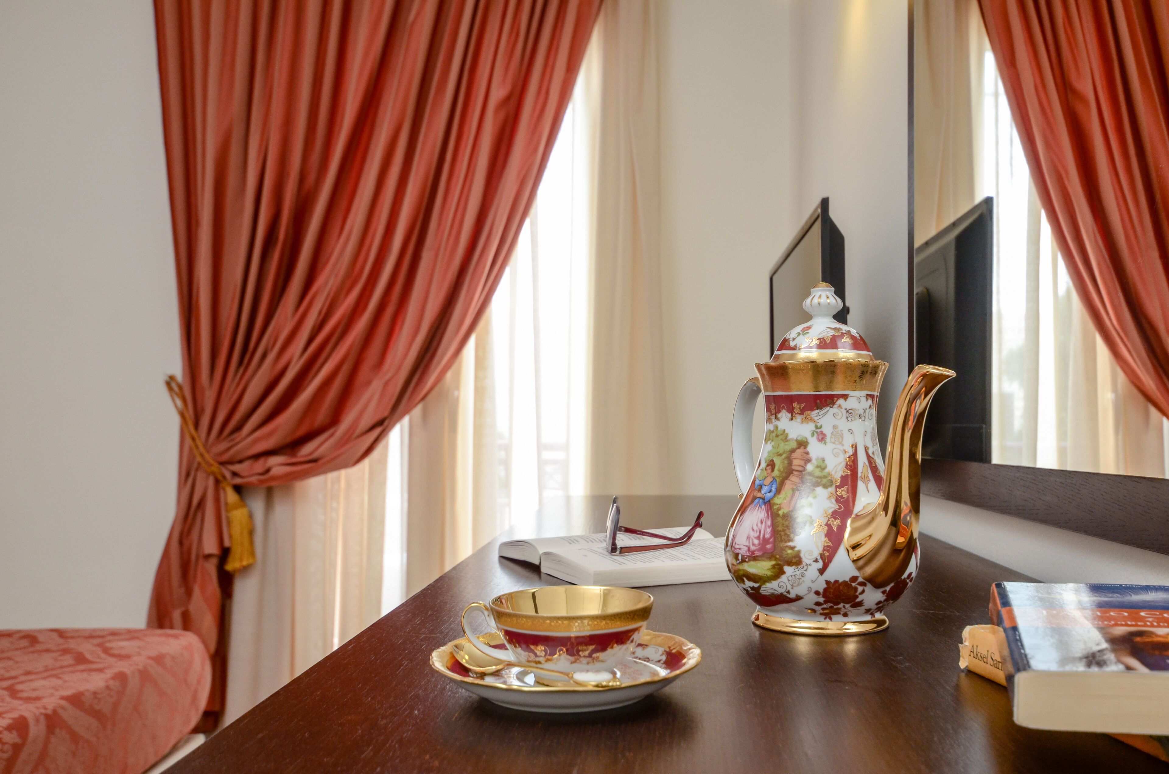 A room with a wooden table, a decorative teapot, a cup, and a book.