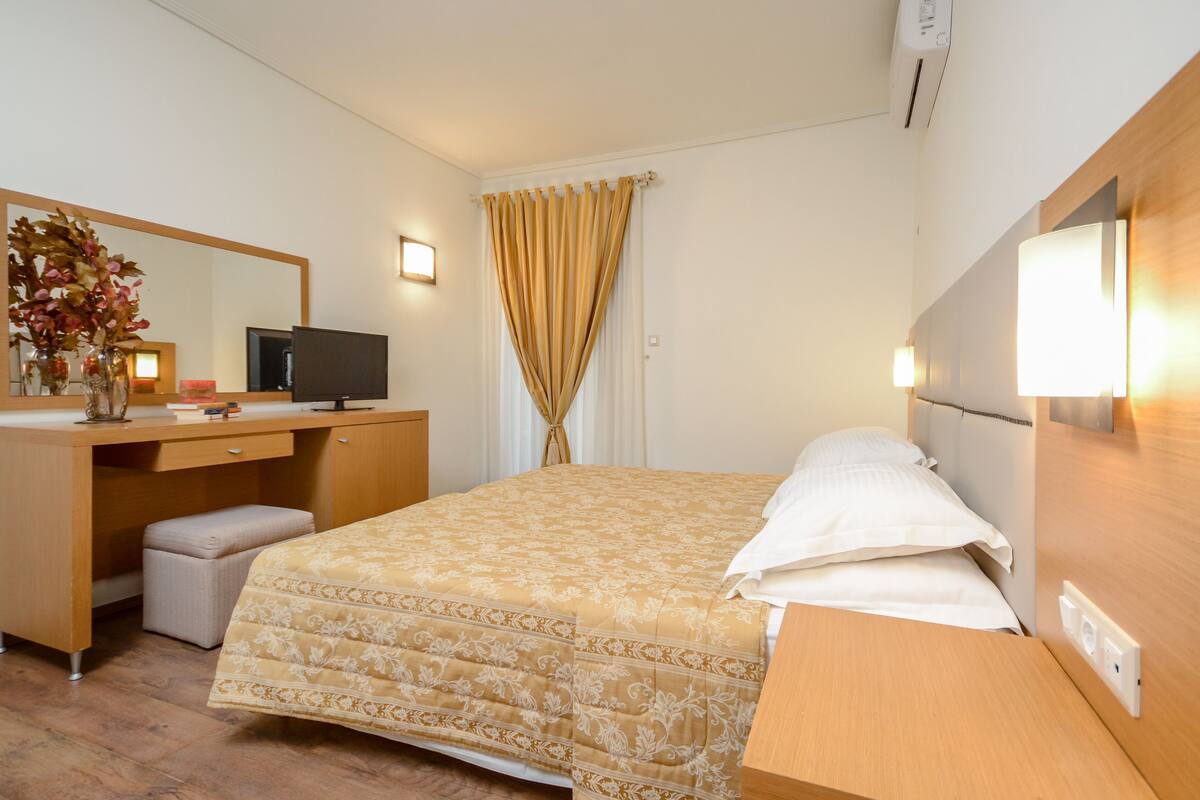 A hotel room with a bed, a desk, a television, and a mirror.