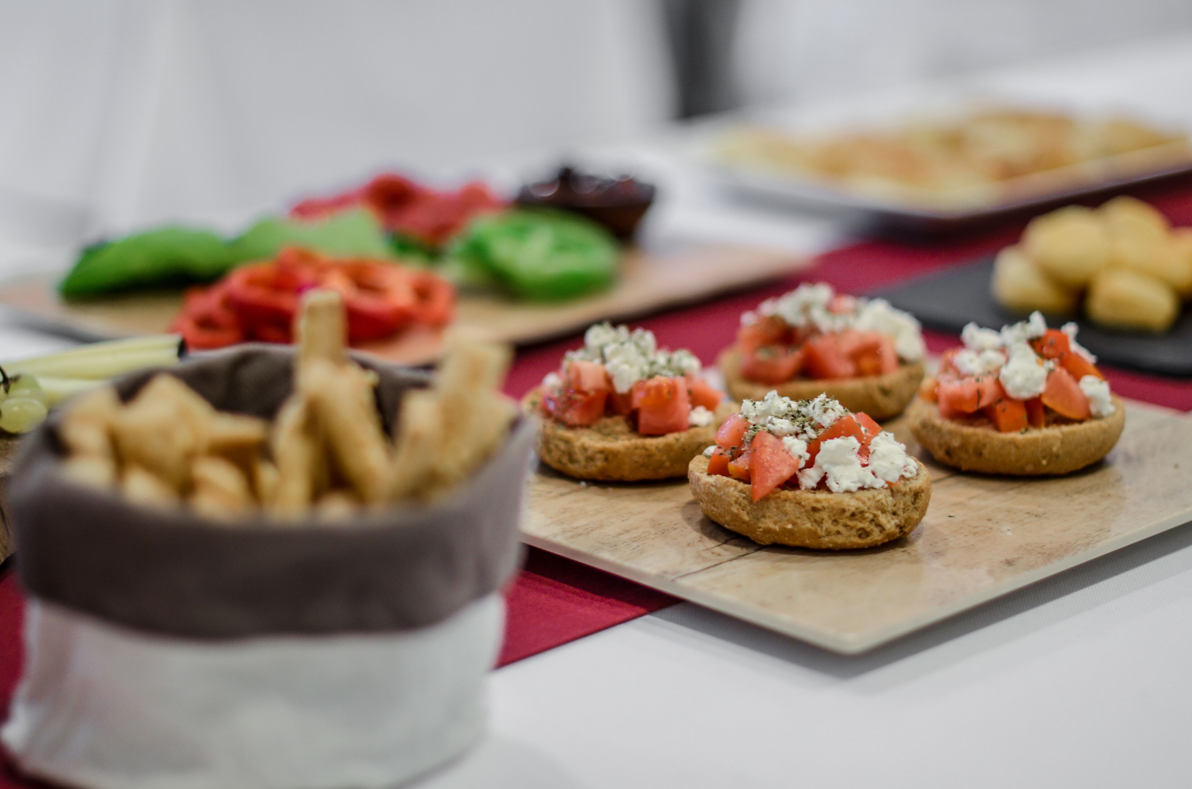 A variety of appetizers on a wooden board, including items topped with tomatoes and cheese.