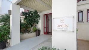 A boutique hotel entrance with a sign reading "aeolis boutique hotel," a covered entrance, and potted plants. - Aeolis Boutique Hotel (Naxos)
