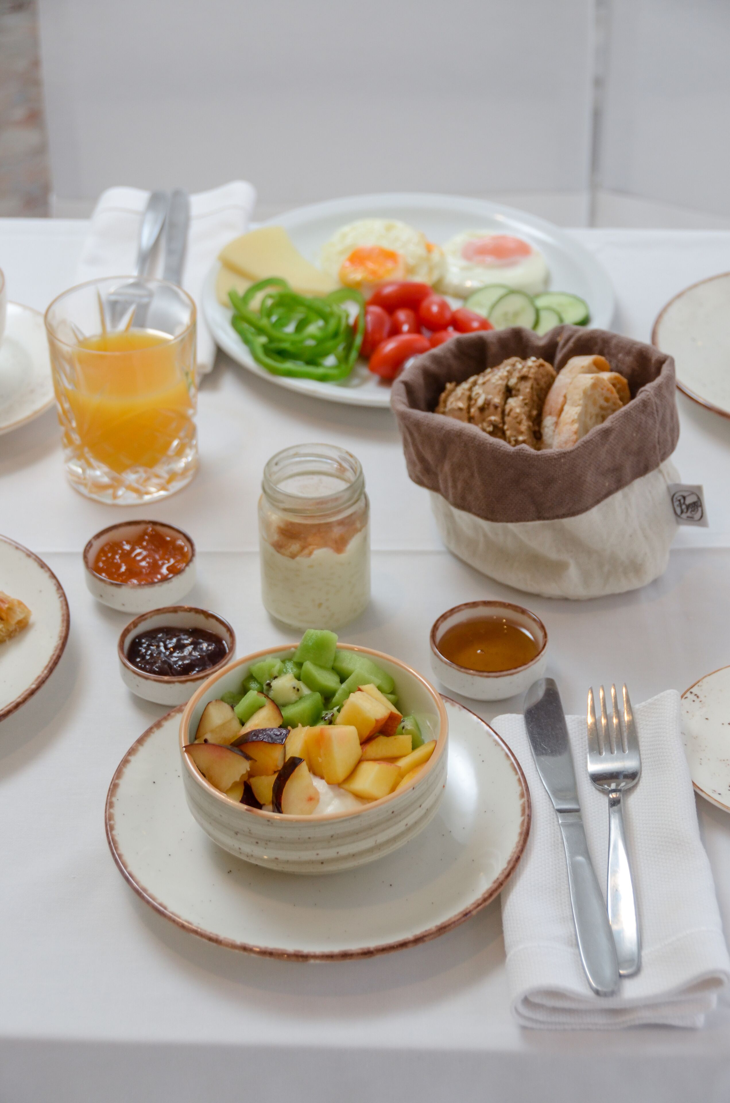 A breakfast setting with a variety of foods including fruits, vegetables, eggs, and bread.