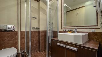 A modern bathroom with a glass-enclosed shower, a white sink, and a large mirror above it.