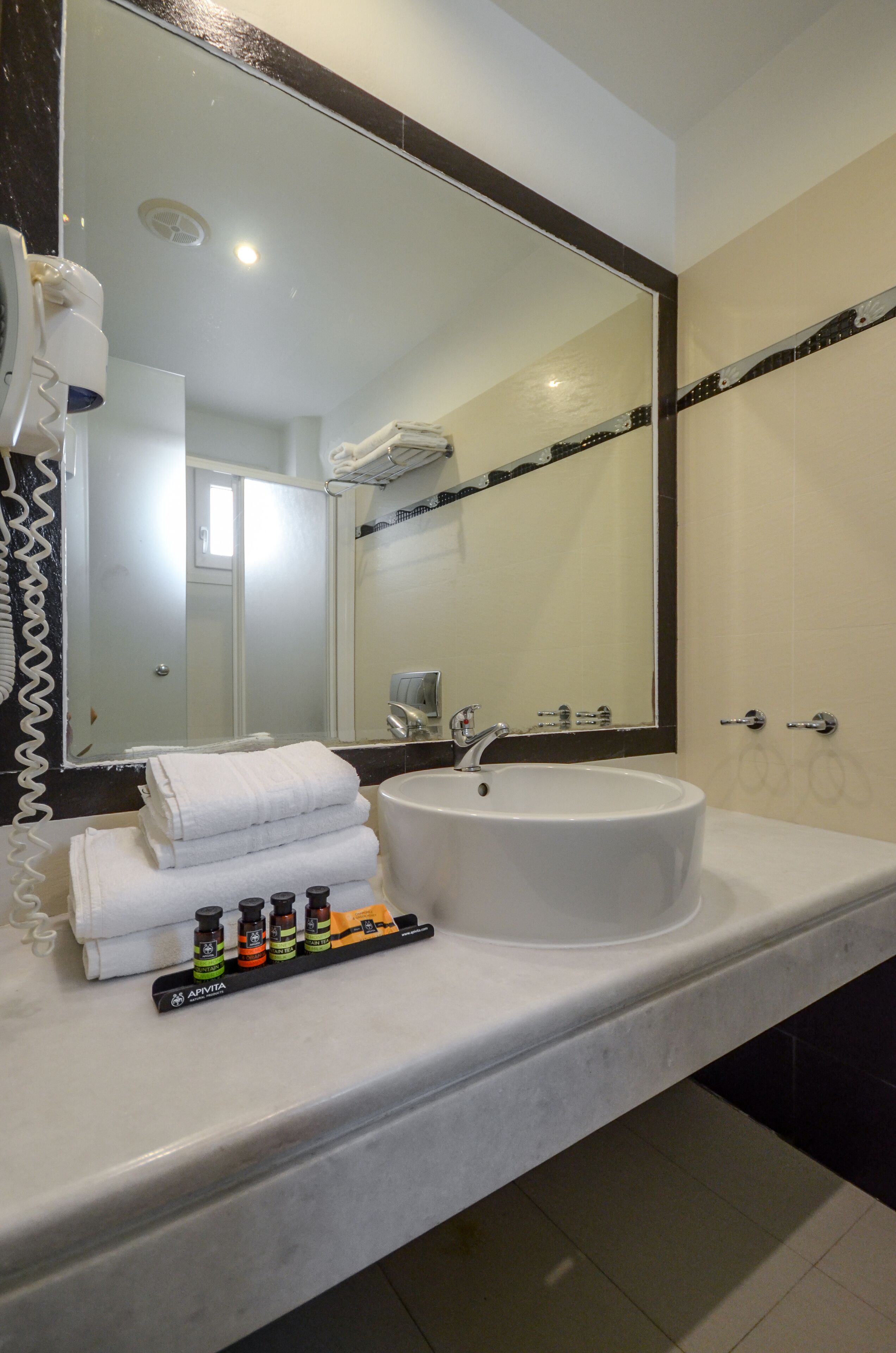 Une salle de bain avec un lavabo blanc, un grand miroir et un porte-serviettes.