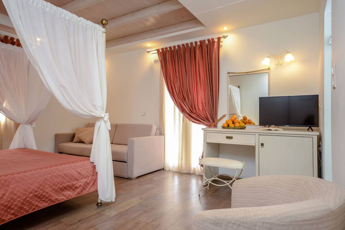 A bedroom with a bed, a desk, a chair, a television, and a wardrobe.
