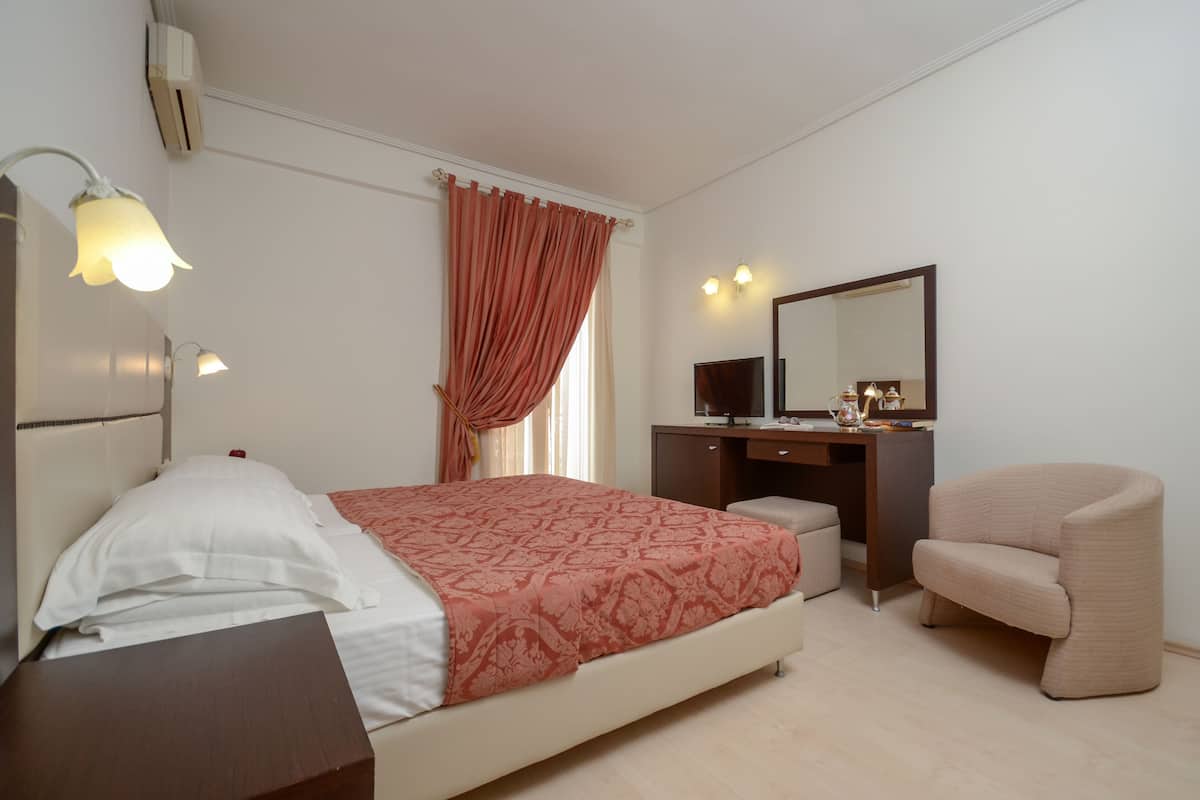 A bedroom with a bed, desk, chair, and a mirror.