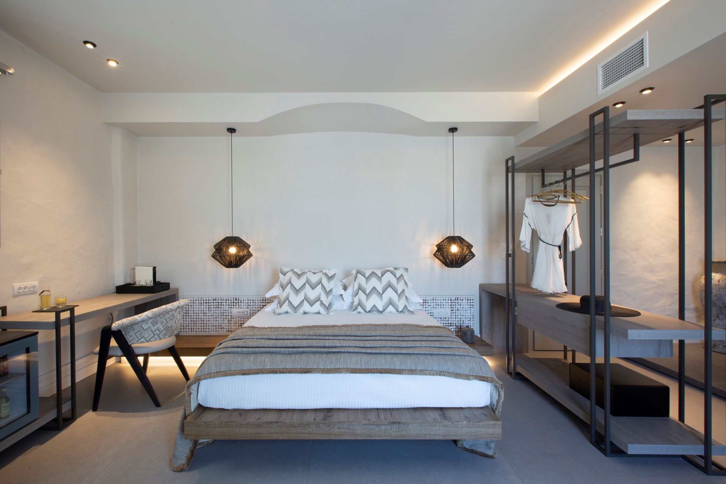 A modern bedroom with a bed, bedside tables, a chair, and a wardrobe.
