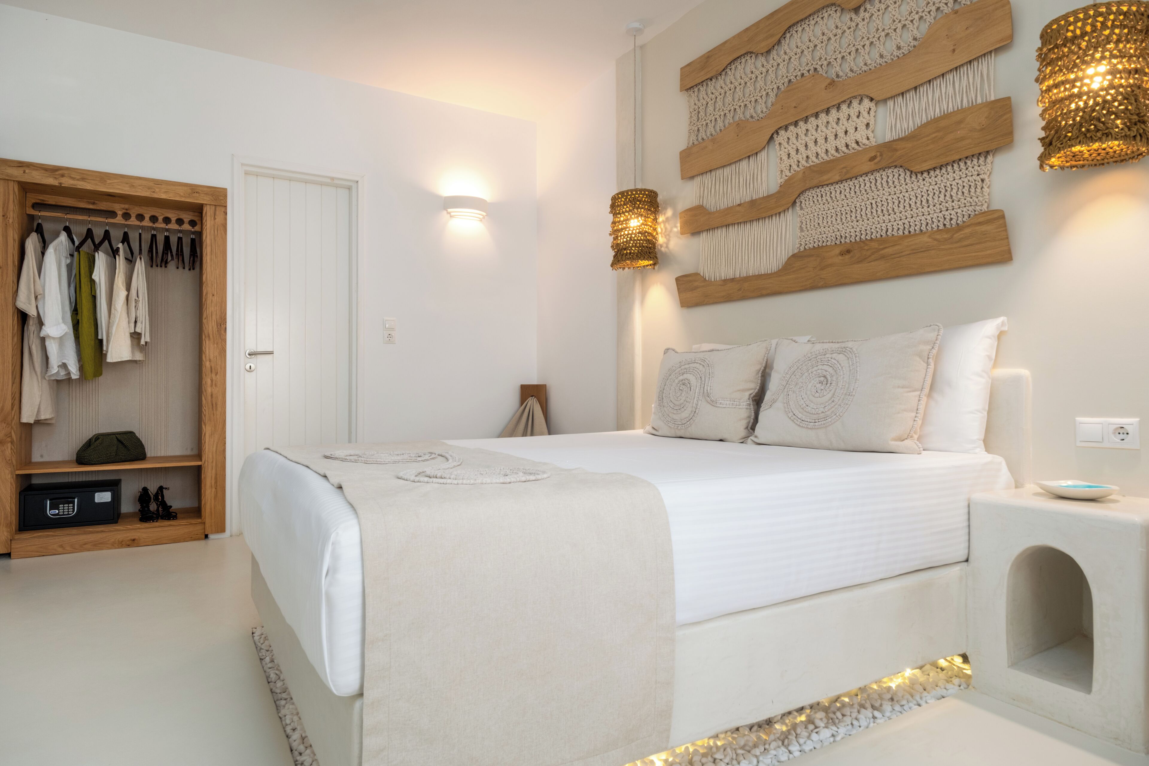A bedroom with a bed, a wooden wardrobe, a wall-mounted light fixture, and a decorative wall piece.