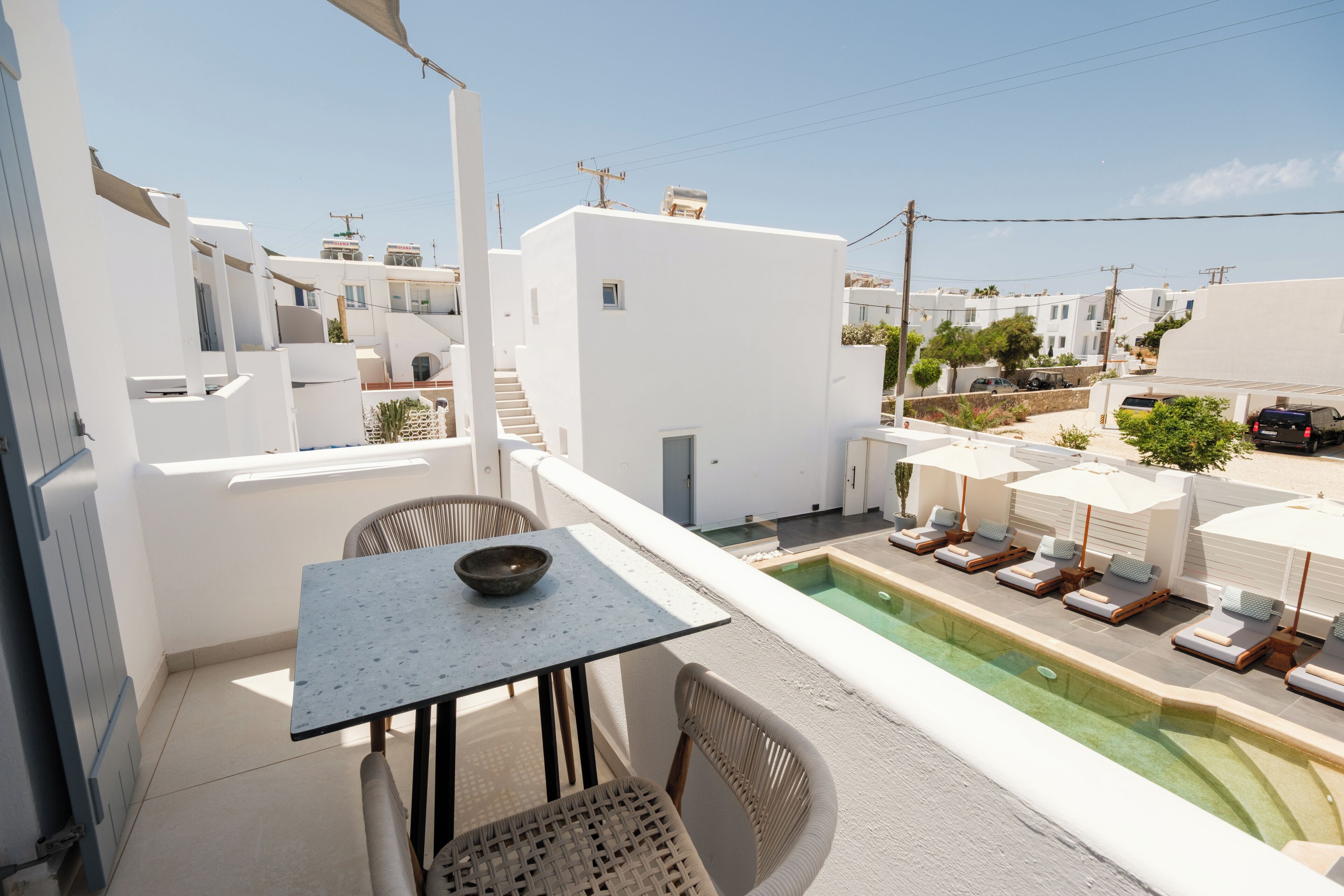 Une terrasse sur le toit avec une piscine, des bâtiments blancs et des chaises longues.