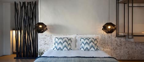 A bedroom with a bed, two wall-mounted lamps, a decorative wall, and a wooden floor.