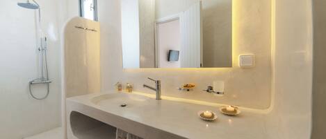 Un baño moderno con un lavamanos grande, un espejo, una ducha y un perchero para toallas.