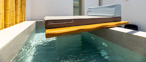 A floating bed in a water-filled room with a bamboo wall and a small window.